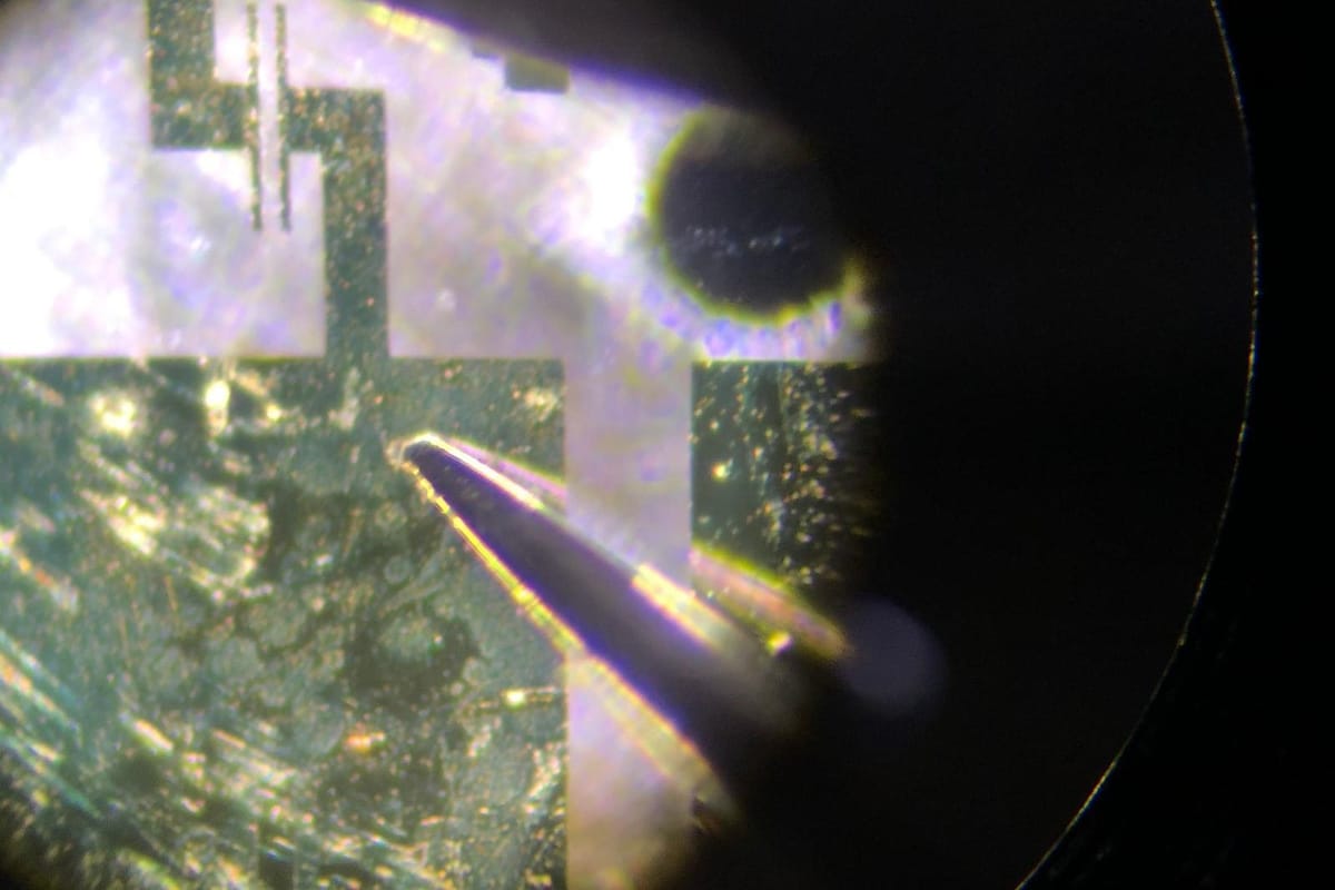 A microscope view of a probe tip resting on a contact pad.